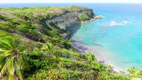 Vuelo-Panorámico-Cruzando-El-Acantilado-En-Playa-Bretona-Maria-Trinidad-Sánchez,-Con-Vista-Al-Viejo-Cabo-Francés-Y-Las-Aguas-Azules,-Y-La-Hermosa-Vegetación-De-La-Zona