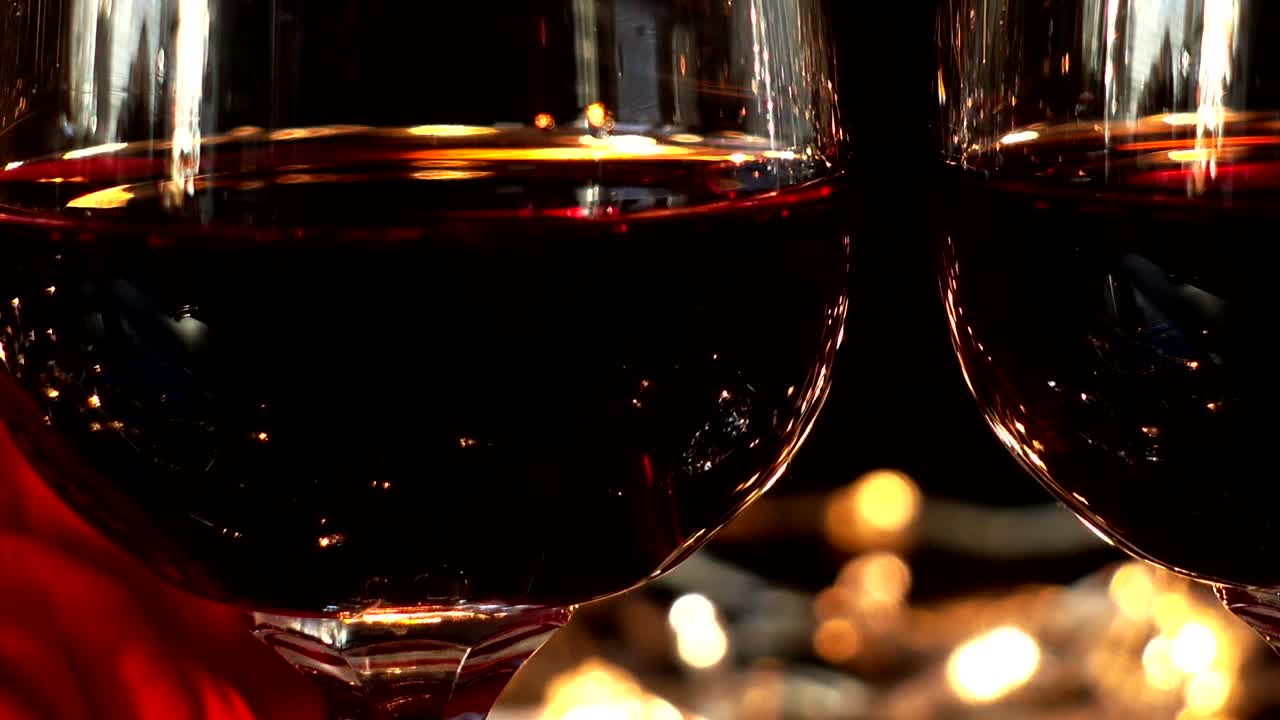 Bicchieri da vino e rosa sullo sfondo di ghirlande luminose.