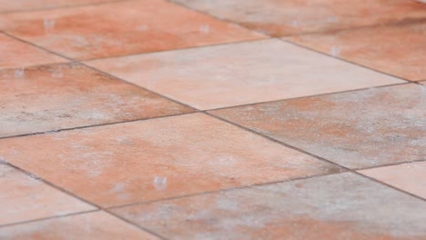 detail of raindrops hitting the ground in slow motion over rustic ceramic tiles