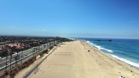 drone panning left down the beach viewing the pier in huntington beach california