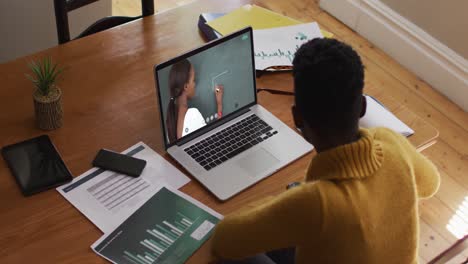 estudiante afroamericana usando una computadora portátil en una videollamada con una maestra