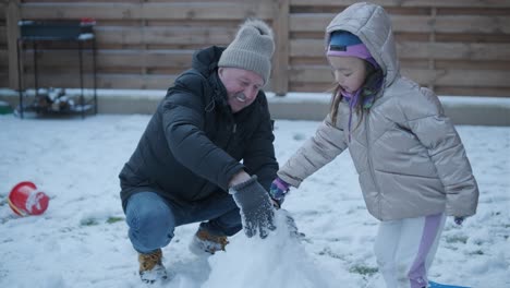 grandfather and granddaughter having fun in the snow