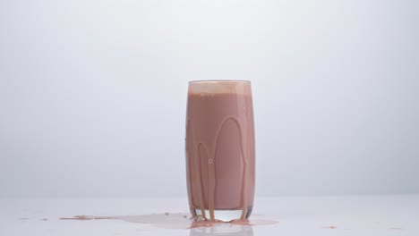 ice cubes falling in a glass of chocolate milk on white background