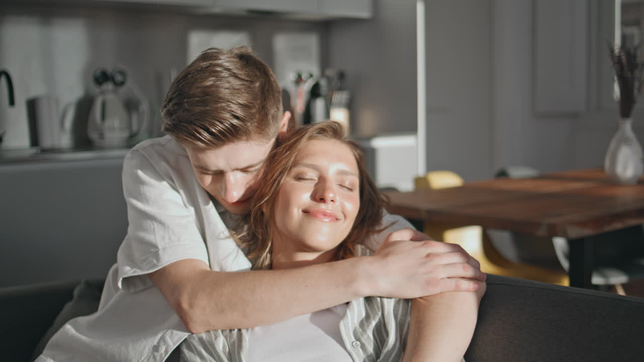 Happy partners relaxing sofa together closeup. Affectionate husband embracing