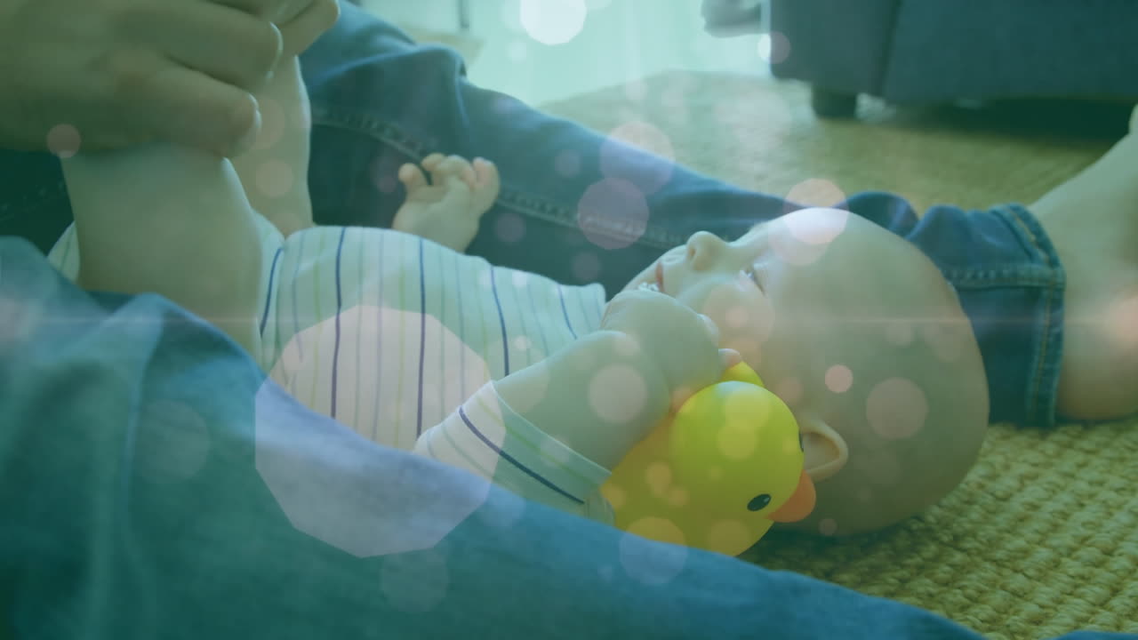 아기와 함께 놀고 있는 백인 어머니 위에 떠다니는 점들의 애니메이션