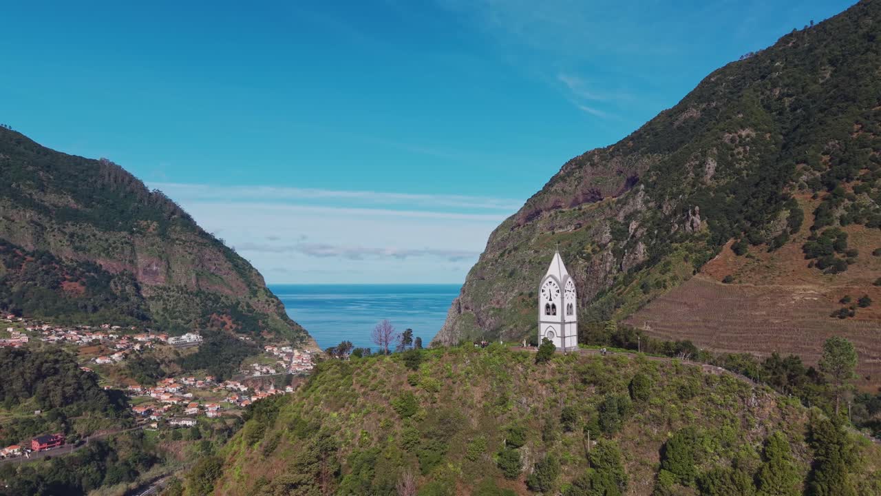 Veduta aerea della cappella di Nossa Senhora de Fátima sopra la valle di São Vicente con l'Oceano Atlantico sullo sfondo, circondata da montagne verdi sull'isola di Madeira