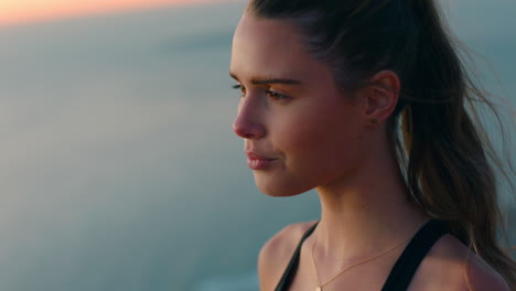 beautiful woman on mountain top looking at view of ocean at sunrise enjoying peaceful contemplation with wind blowing hair