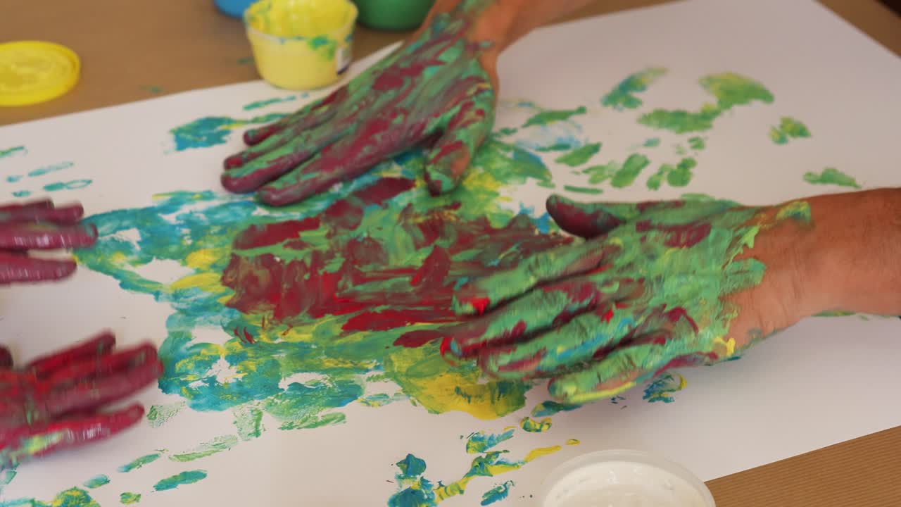 Hands of adult man and little girl play with colors and handprints