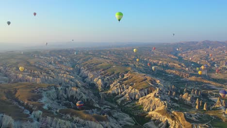 Muchos-Globos-Aerostáticos-Flotando-Sobre-El-Paisaje-De-Capadocia,-Antena-Panorámica-Hacia-Atrás