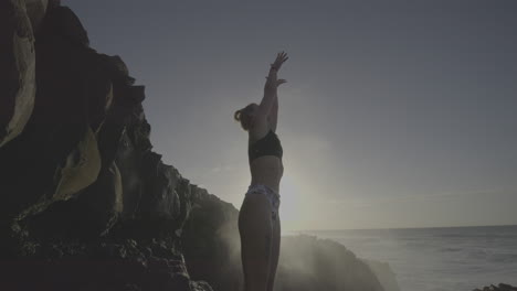 woman on a rocky coastline at sunrise/sunset
