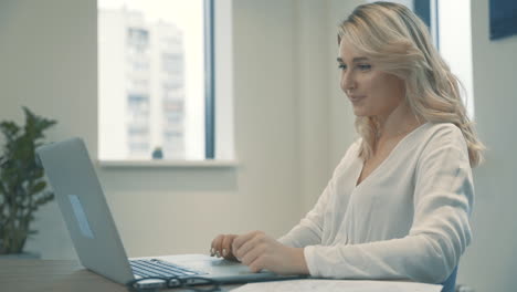 mujer rubia bastante joven que tiene una videollamada de negocios y trabaja desde casa