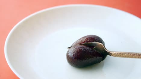 cutting black  indian sweet with a spoon ,