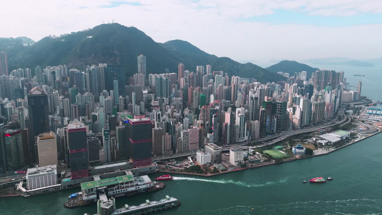 Pemandangan udara panorama gedung pencakar langit dan Pelabuhan Victoria di pusat kota Hong Kong pada hari yang cerah, menampilkan garis langit dan tepi laut yang ikonik