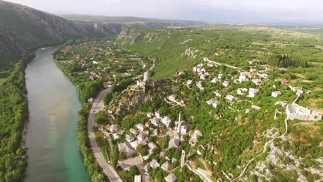 una vista aérea muestra automóviles circulando por la carretera entre el río neretva y el pueblo de pocitelj bosnia