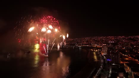 Aerial view establishing Valparaiso at night with the New Year&#039;s Eve fireworks display, city illuminated by lights and sparkles
