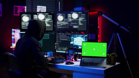 green screen laptop used by hacker in underground hideout to write lines of code
