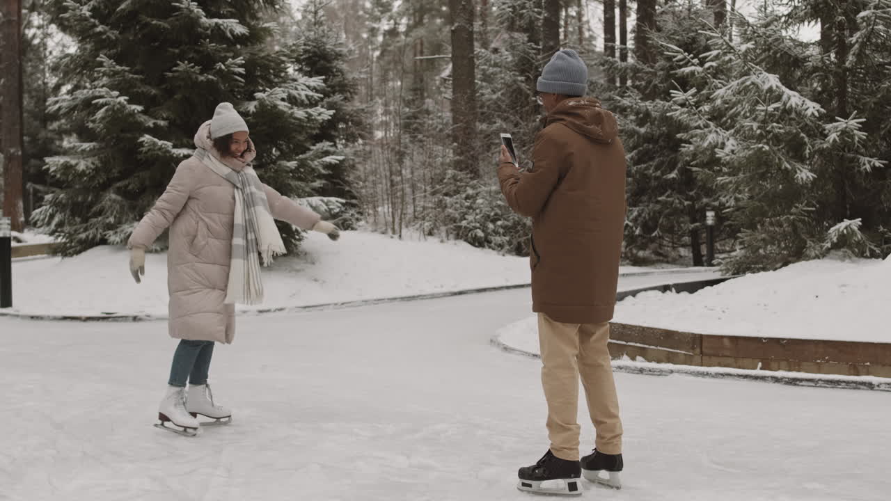 pareja patinando sobre hielo y tomando fotos en el parque de invierno