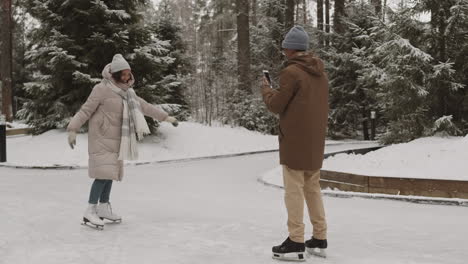 couple ice skating and taking photos in the winter park