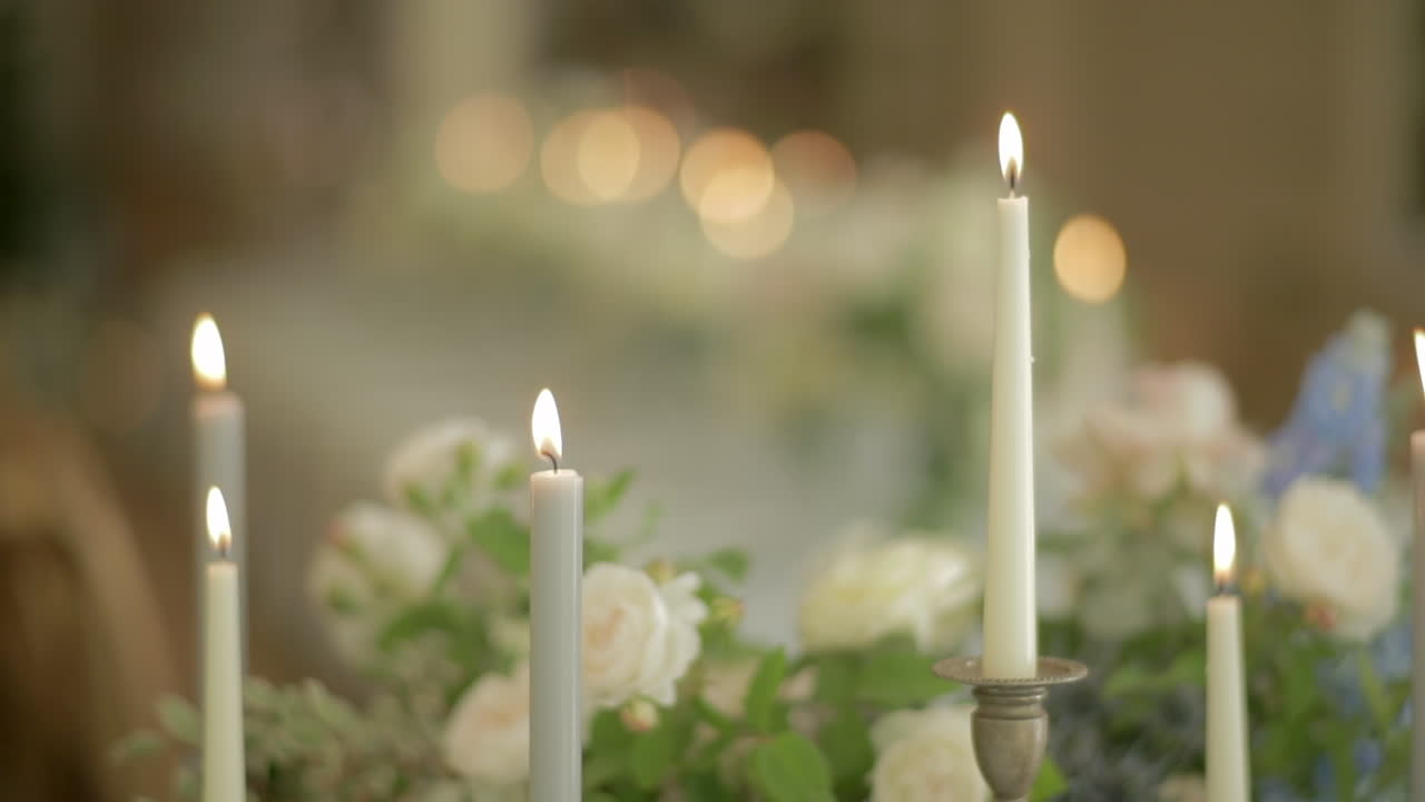 velas altas ardiendo con rosas blancas en el fondo