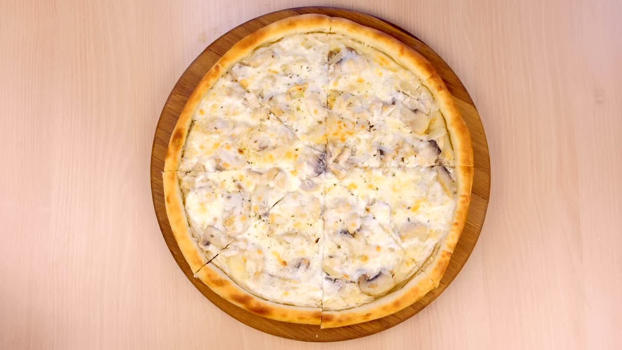 cortando pizza con setas, champignones y queso en una tabla de madera en la mesa.