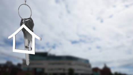 Animation-of-silver-house-model-and-key-over-defocused-building-against-cloudy-sky