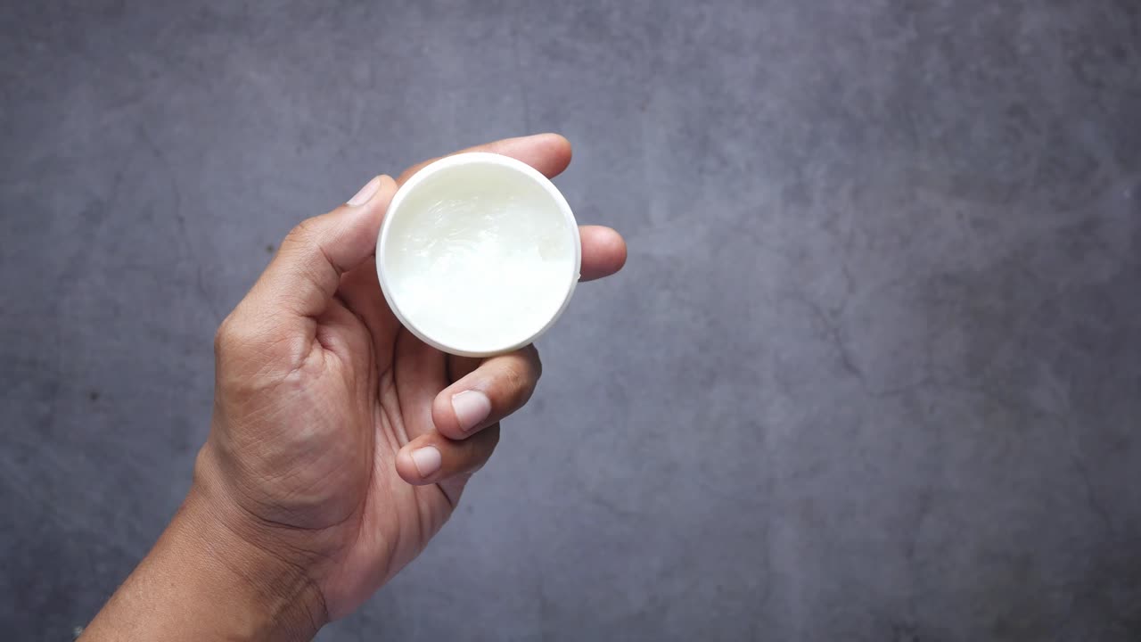 크림 을 담은 용기 를 들고 있는 손