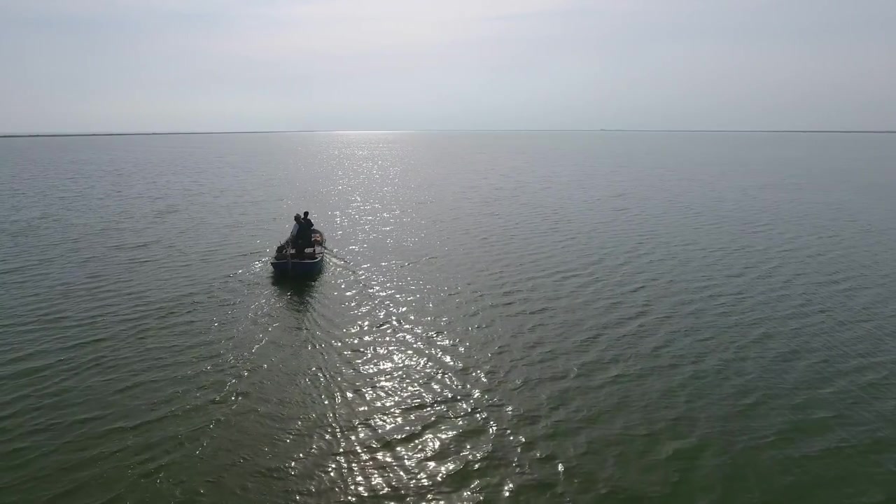 Due pescatori che remano su una piccola barca su un lago calmo