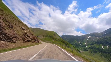 Langsame-Kamerabewegung-Einer-Straße-Im-Vordergrund-Mit-Hohen-Bergen-Im-Hintergrund-Und-Einem-Klaren-Blauen-Himmel