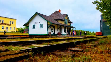pioneer village interactive actors waiting at station in costume early 1900s next to hotel and grain processing mill with storage train car closeup of railway tracks room for text summer day 4k60