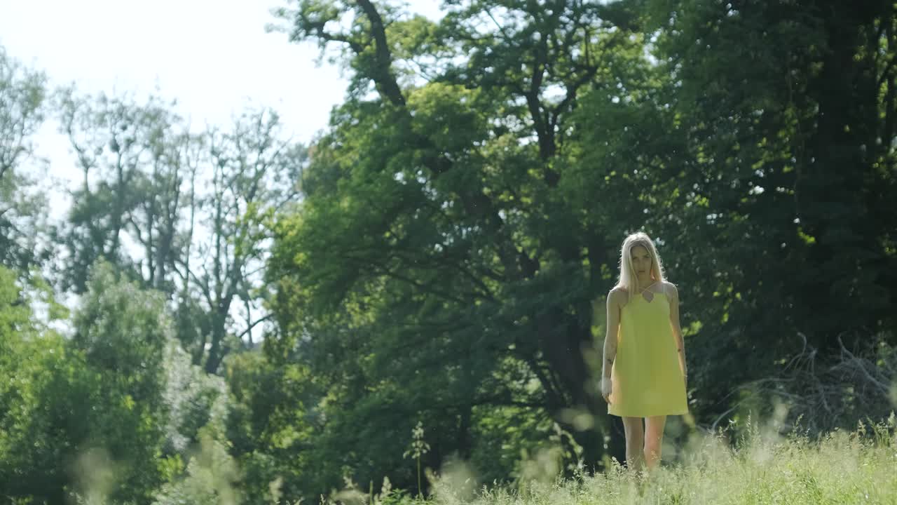 아름다운 젊은 소녀가 자유의 춤을 추고 있습니다. 여름 공원에서 뒷면에 나무가 있습니다.