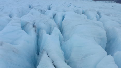 Slow-aerial-shot-over-deep-cracks-in-blue-ice-glacier