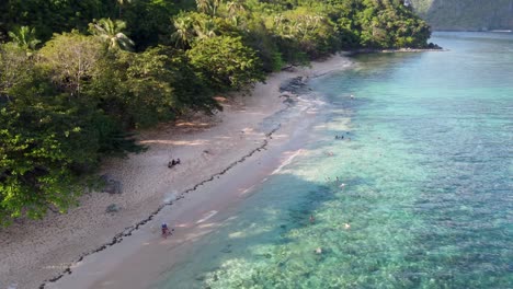 people swimming and snorkeling at tropical beach of dilumacad helicopter island