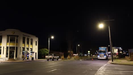 vehicles pass through a lit intersection at night