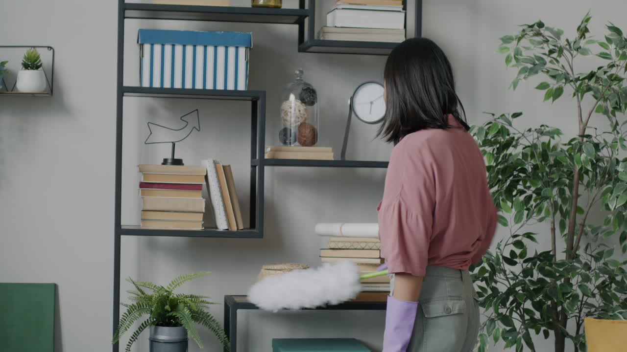Woman Cleaning Bookshelves in Living Room