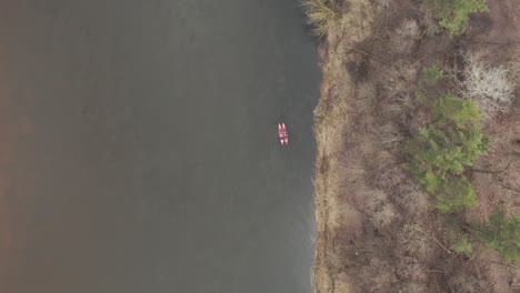 aerial: kayakers swimming close to each other on a river in early spring time