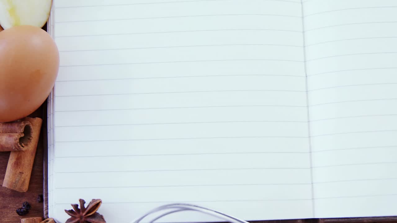 Book, eggs, spices, spoon and whisker kept on a table 4k