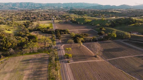 imágenes aéreas sobre una carretera rural en santa ynez, california, tierras de cultivo del país del vino como se ve desde el cielo, cordillera en el horizonte