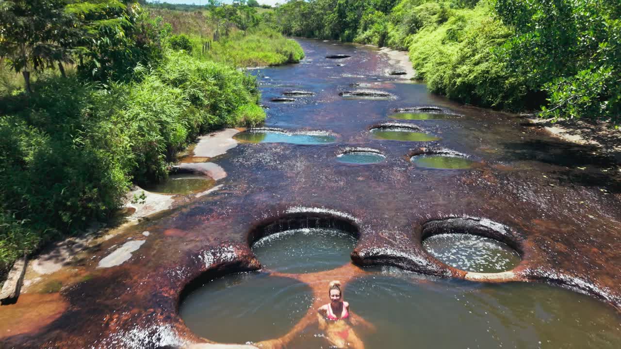 Aerial view of a blonde woman swimming in the natural jacuzzis of las gachas river in colombia