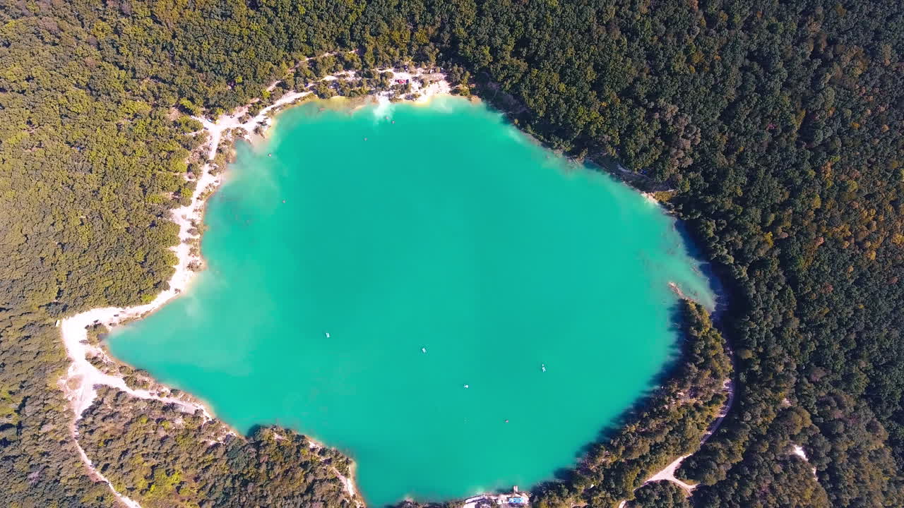 Turquoise spot of the lake in the forest. Wonderful picturesque view over the pond with white sandy banks around. Top view.