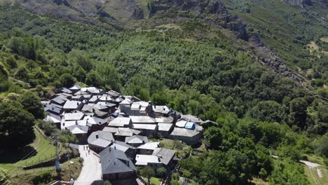 aerial view of stone village with slate roofs surrounded by green mountains