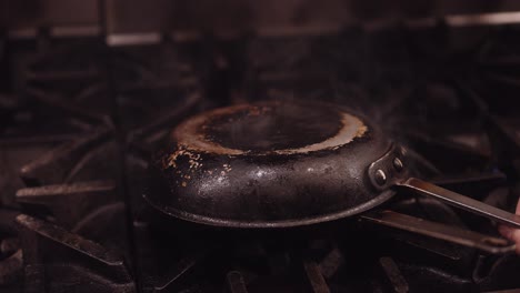 black frying pan is placed upside down on a pan with high flames coming out while the chicken is being cooked