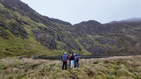 grupo de caminantes por la ladera de la montaña en el lago coumdala en las montañas de comeragh waterford irlanda en un día frío de invierno