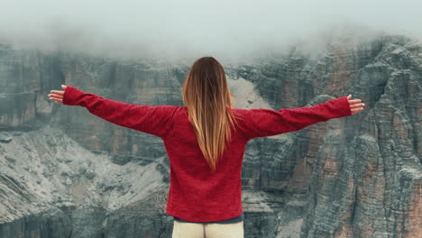 hiker standing with outstretched arms at pordoi pass, absorbing breathtaking dolomites landscape, embodying freedom and personal discovery amid alpine majesty