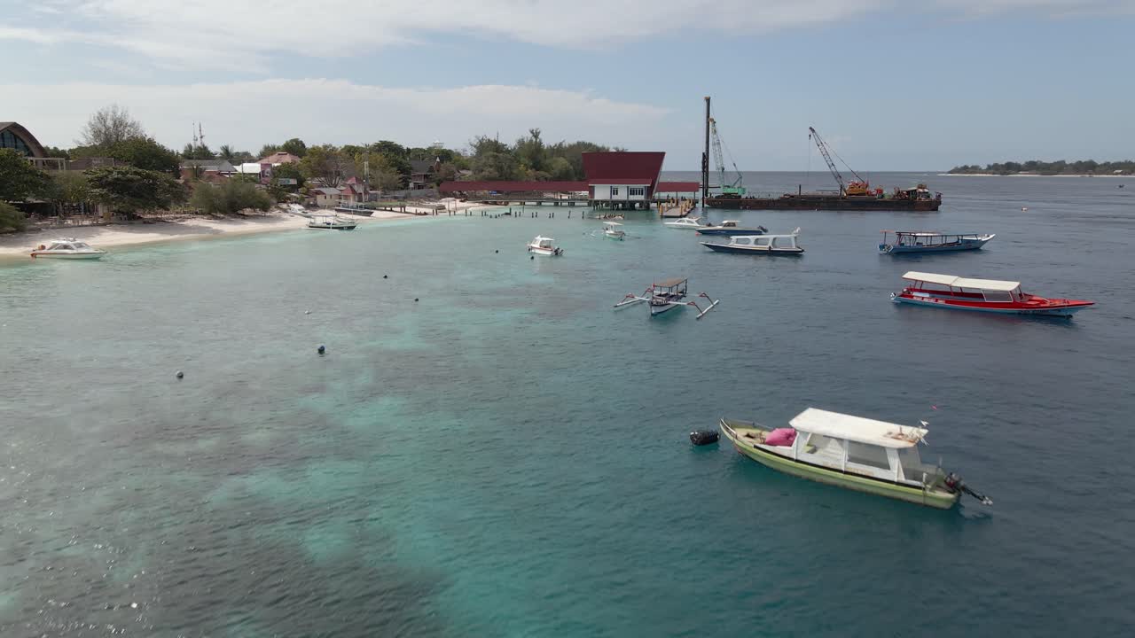 Sorvolo aereo di barche ancorate e di un'imbarcazione industriale per condotte in fase di attracco sul molo dell'isola di Gili