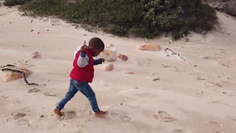 little boy running and playing on the beach in the winter time