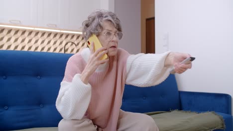senior woman struggling with tv remote and phone call