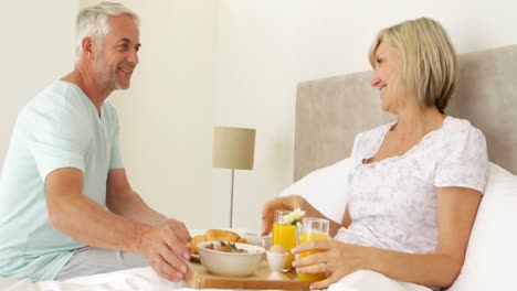 marido romántico trayendo su esposa sonriente desayuno en la cama