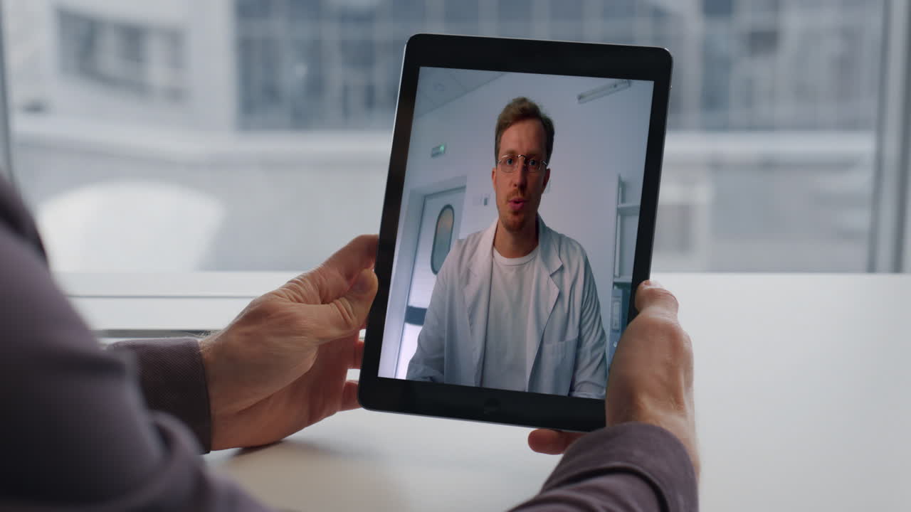 Mani di un manager che guarda lo schermo di un tablet, vista della città, primo piano in una stanza. Uomo medico chatta