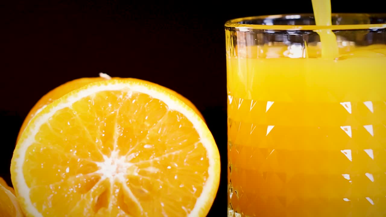 Et detaljeret billede af et glas fyldt med appelsinjuice ved siden af en frisk appelsinskive