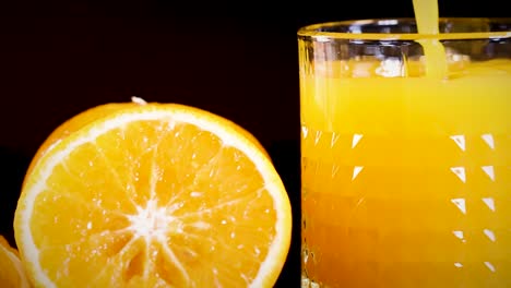 a detailed view of a glass filled with orange juice beside a fresh orange slice.